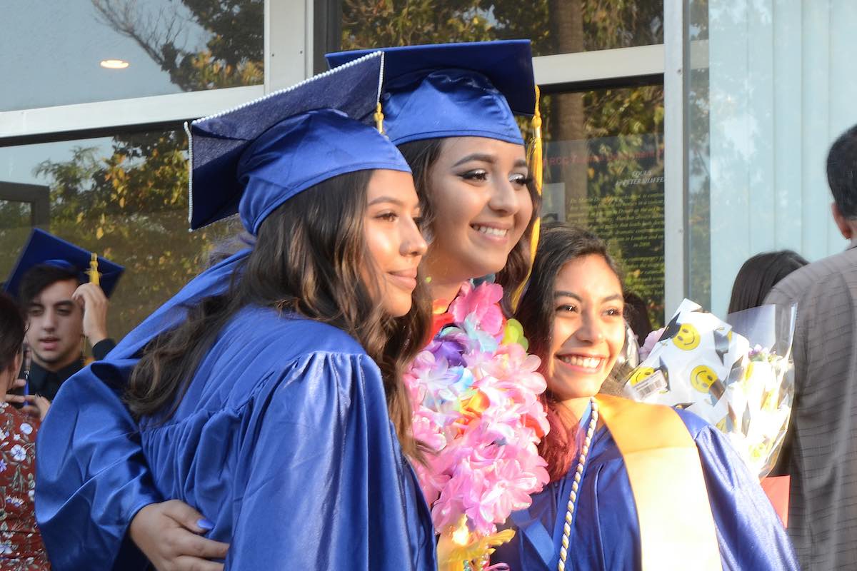 Gateway College and Career Academy graduates in cap and gowns with flowers
