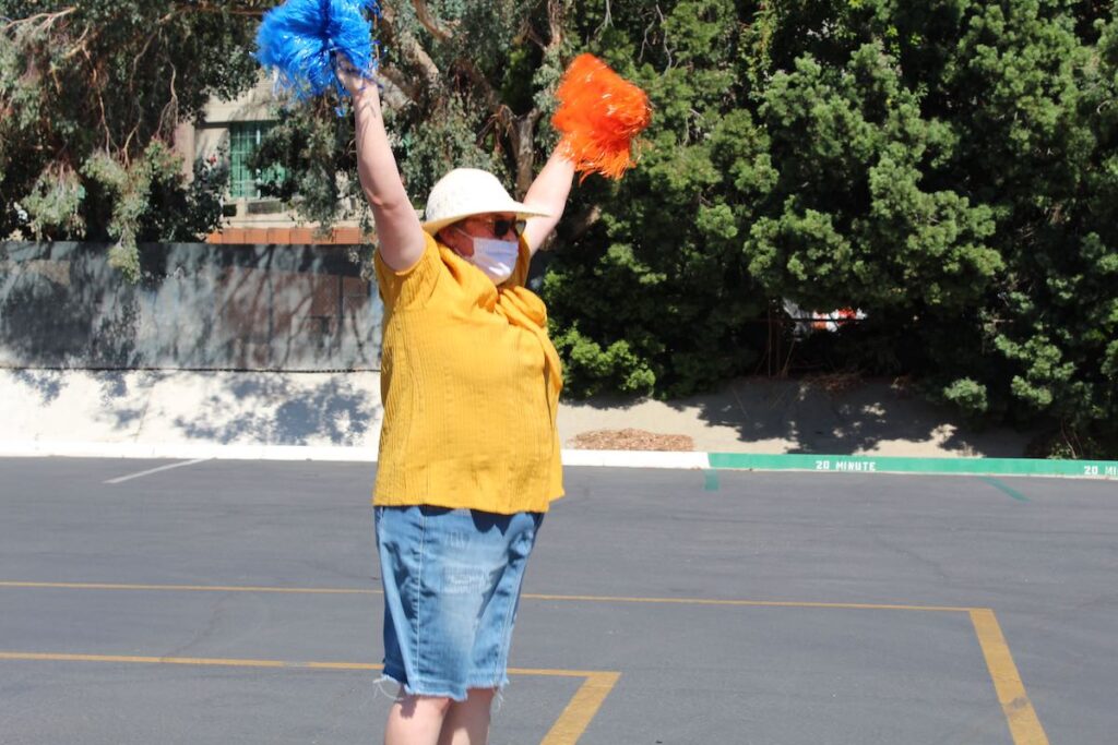 Gateway math teacher Mrs. Loucks stands in the parking lot waving pom poms